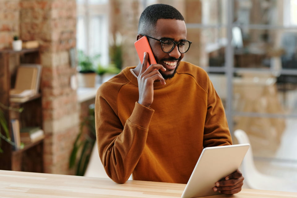 man talking on phone and looking at tablet happy with divorce counseling